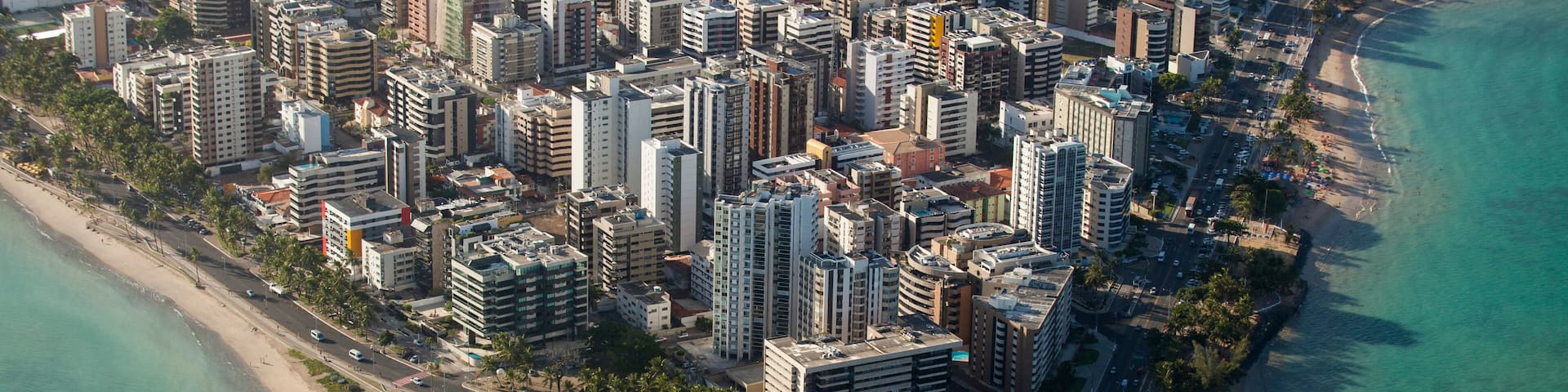 An aerial view of a coastal city with high-rise buildings, a beach, and a marina.