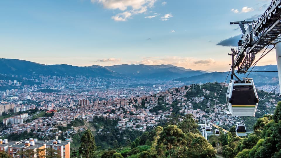 A cable car system, a cityscape, and mountains in the background.