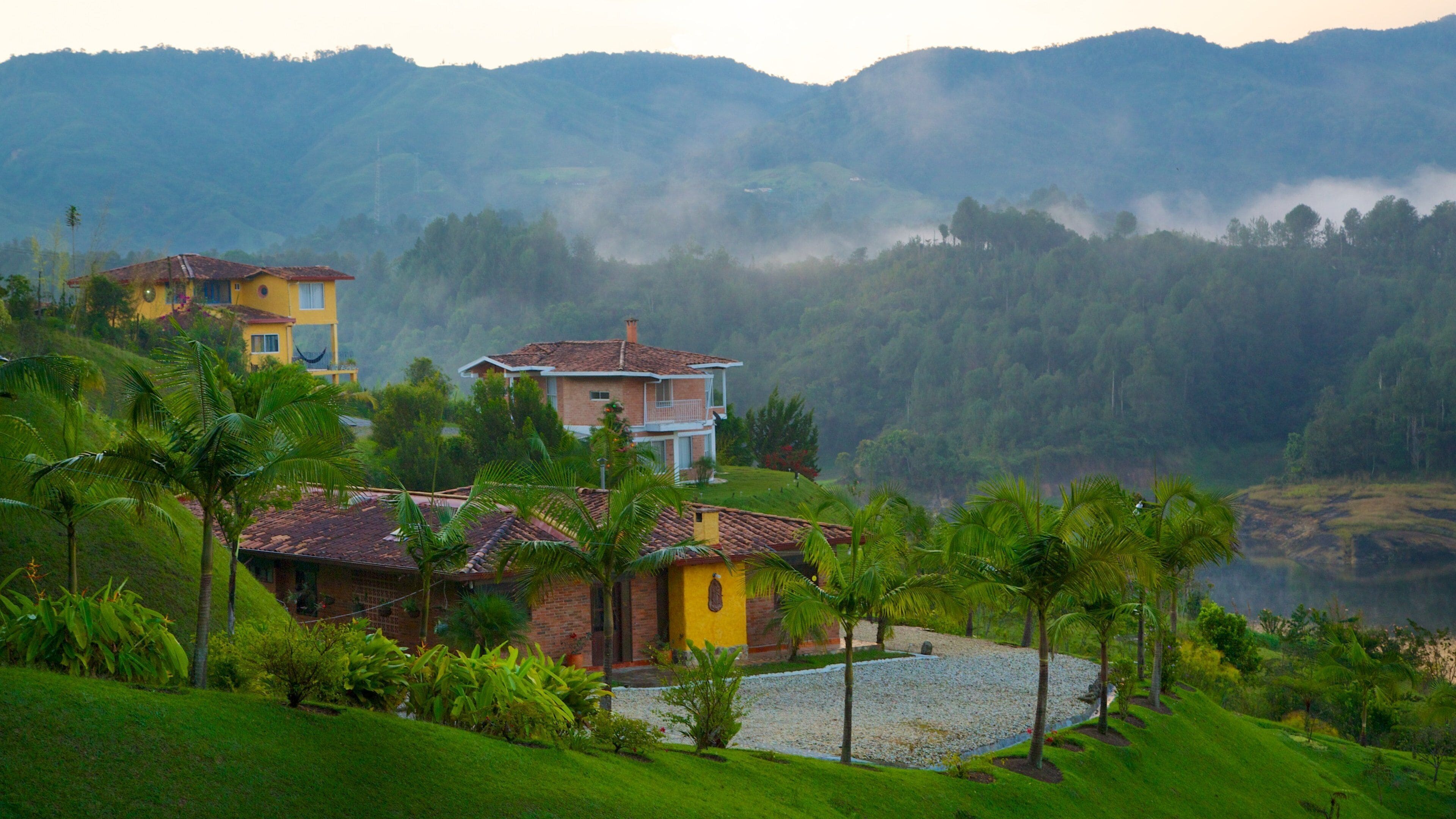 Rock of Guatape which includes mist or fog, tranquil scenes and a house