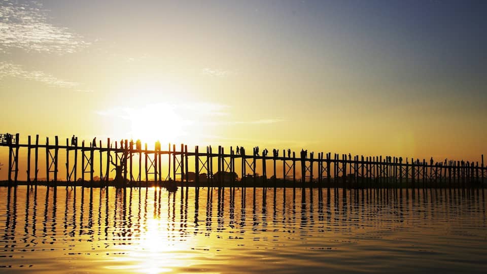 A wooden pier extending into calm water during sunset.