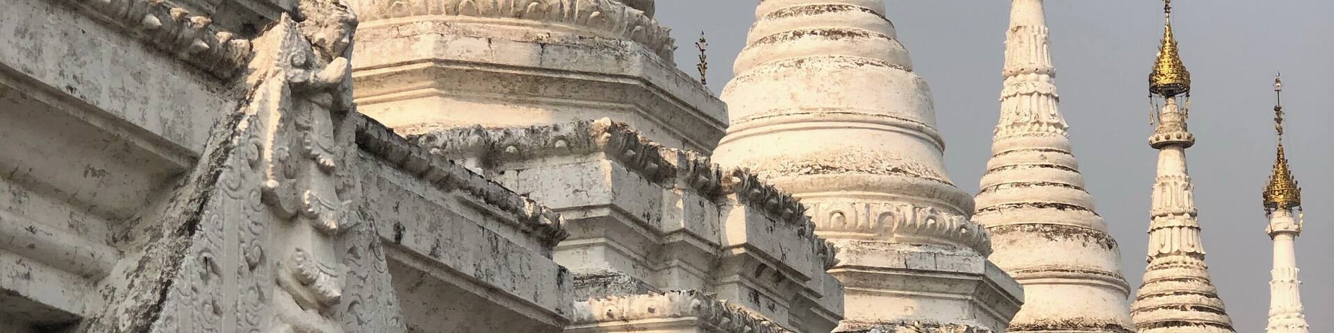 A row of white, intricately carved temple spires with detailed carvings and golden tops.