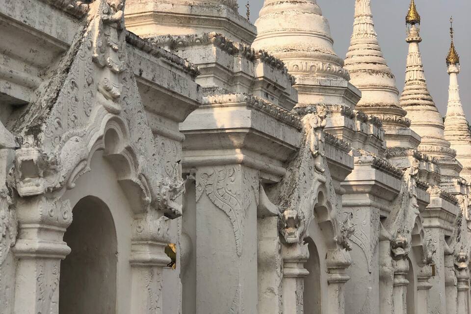 A row of white, intricately carved temple spires with detailed carvings and golden tops.