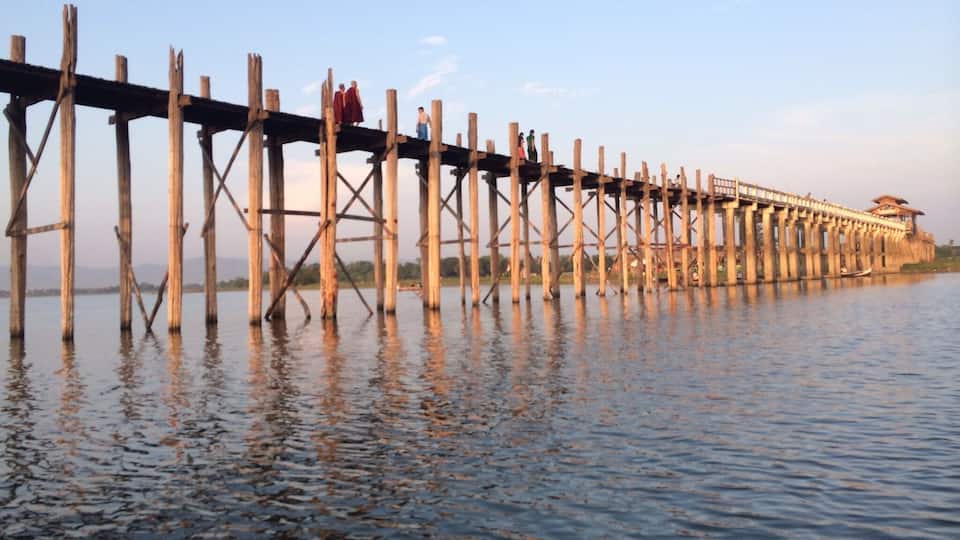 A wooden bridge over water with people walking on it.