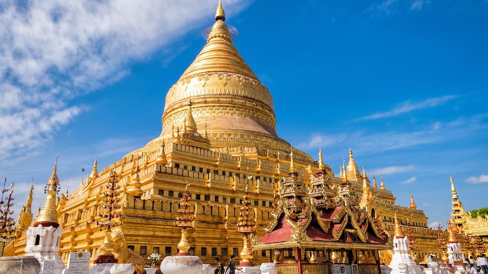 A large golden stupa with intricate designs and multiple smaller stupas in the foreground.