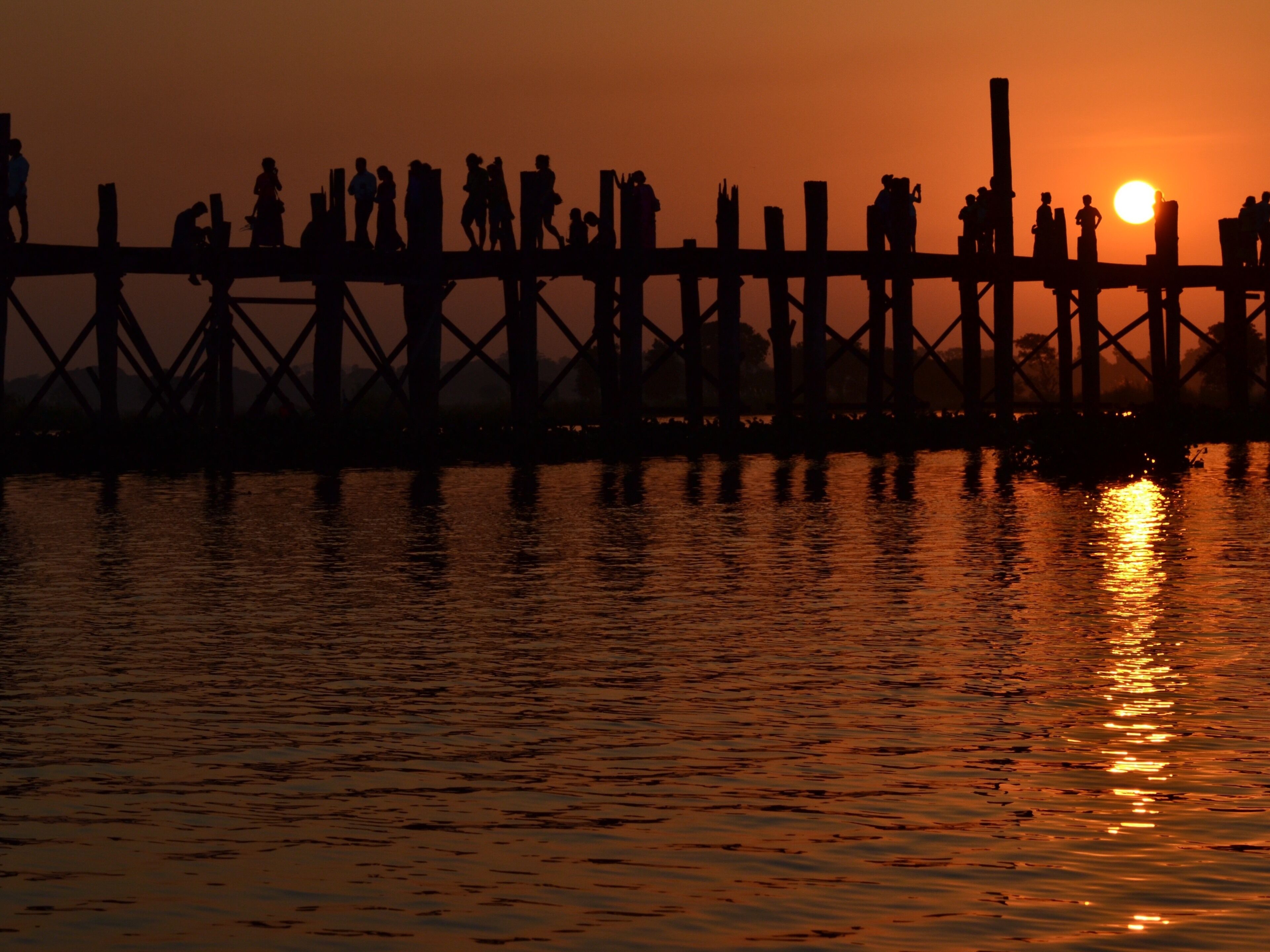 A sunset over a pier with people silhouetted against the sky.