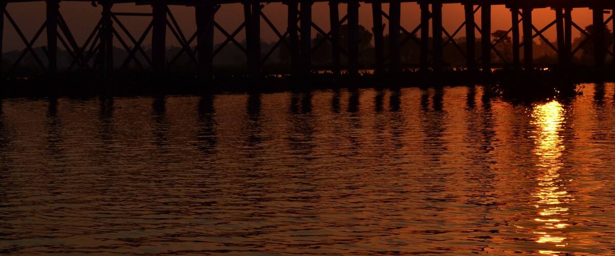 A sunset over a pier with people silhouetted against the sky.