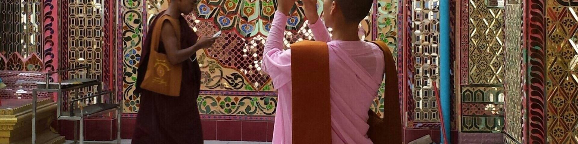 A person taking a photo of a colorful, intricately designed wall with geometric patterns and a central circular motif.