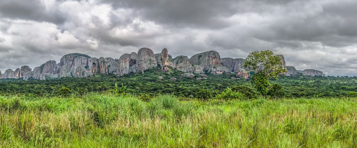 A landscape with a range of rock formations and a tree in the foreground.