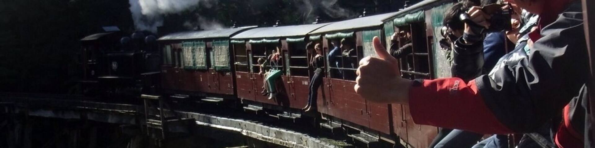 A steam train on a wooden bridge with passengers.