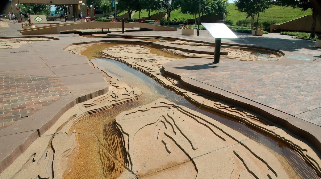A water feature with a flowing design, surrounded by a paved walkway and benches.