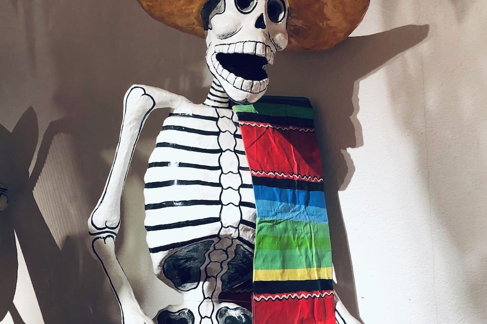 Une silhouette squelettique portant un sombrero et un vêtement rayé aux couleurs vives.