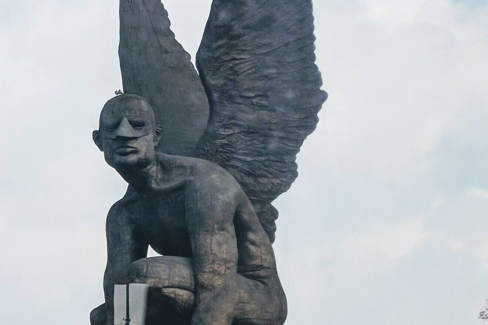 A statue of an angel with wings on a rooftop.