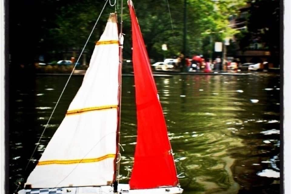 A sailboat with a red and white sail on a river.
