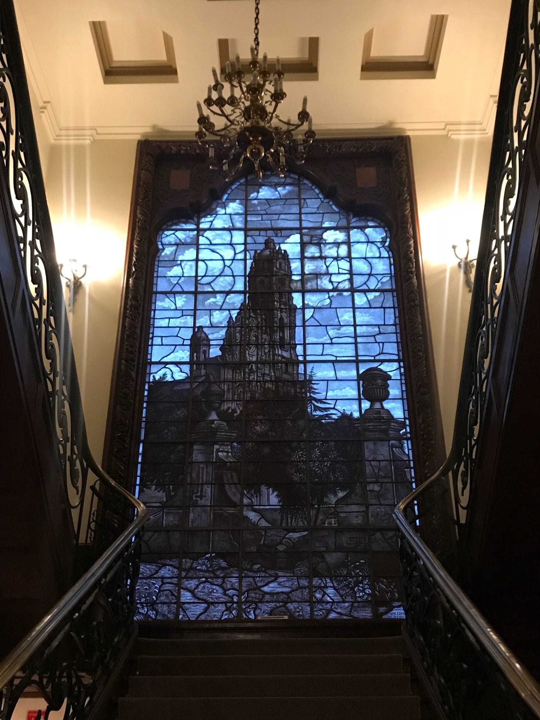A staircase with a stained glass window depicting a historical building.