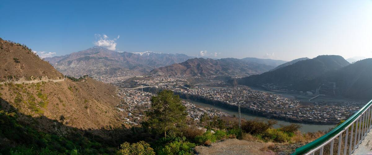 A mountainous landscape with a river, a bridge, and a town.