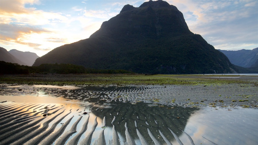 Milford Sound which includes a lake or waterhole, mountains and a sunset