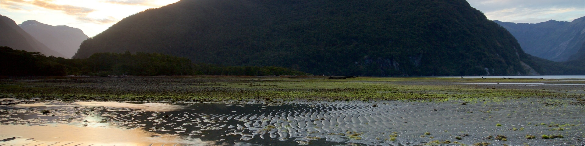 Milford Sound which includes a lake or waterhole, mountains and a sunset