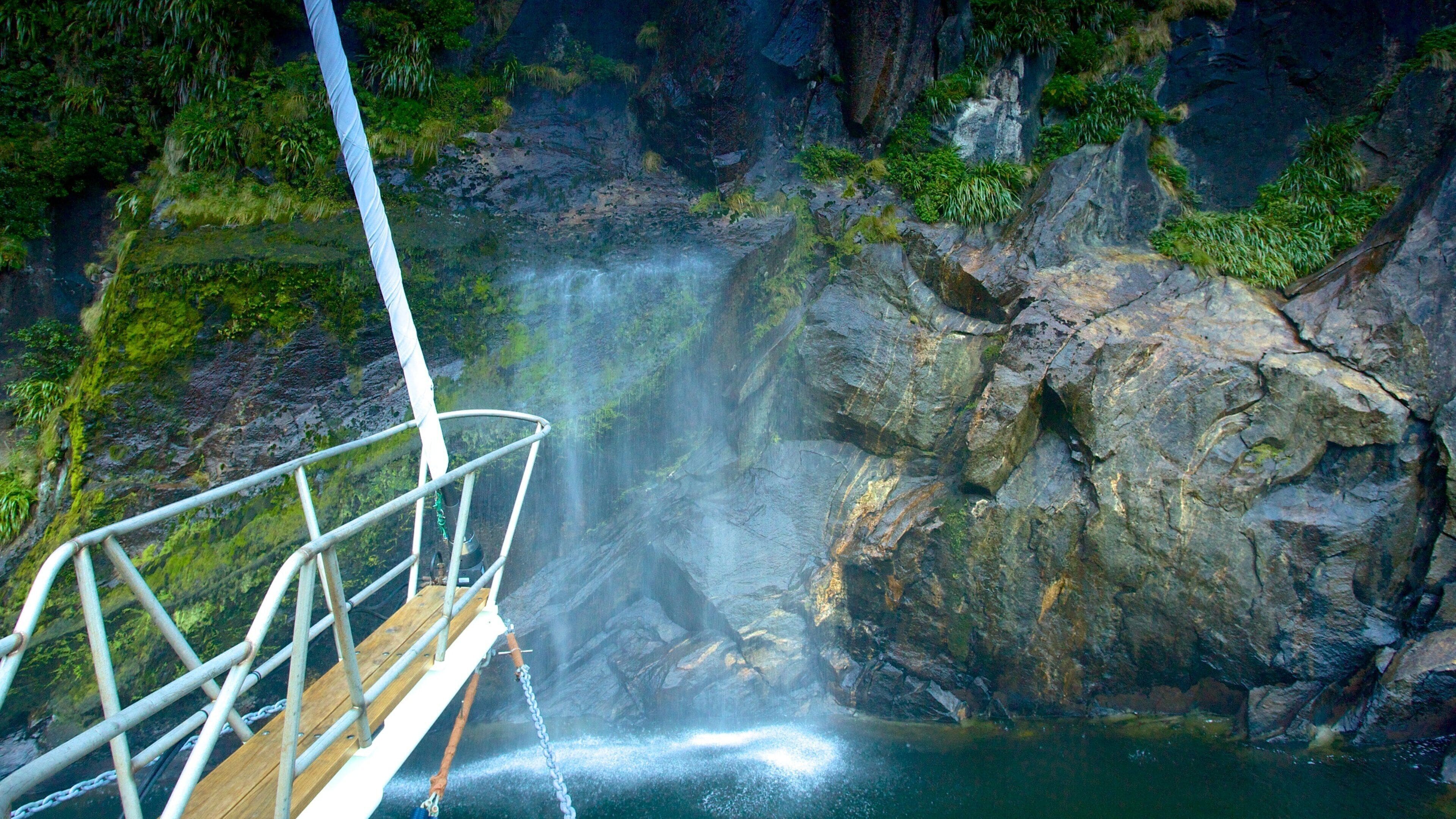 Milford Sound que incluye cataratas, botes y un río o arroyo