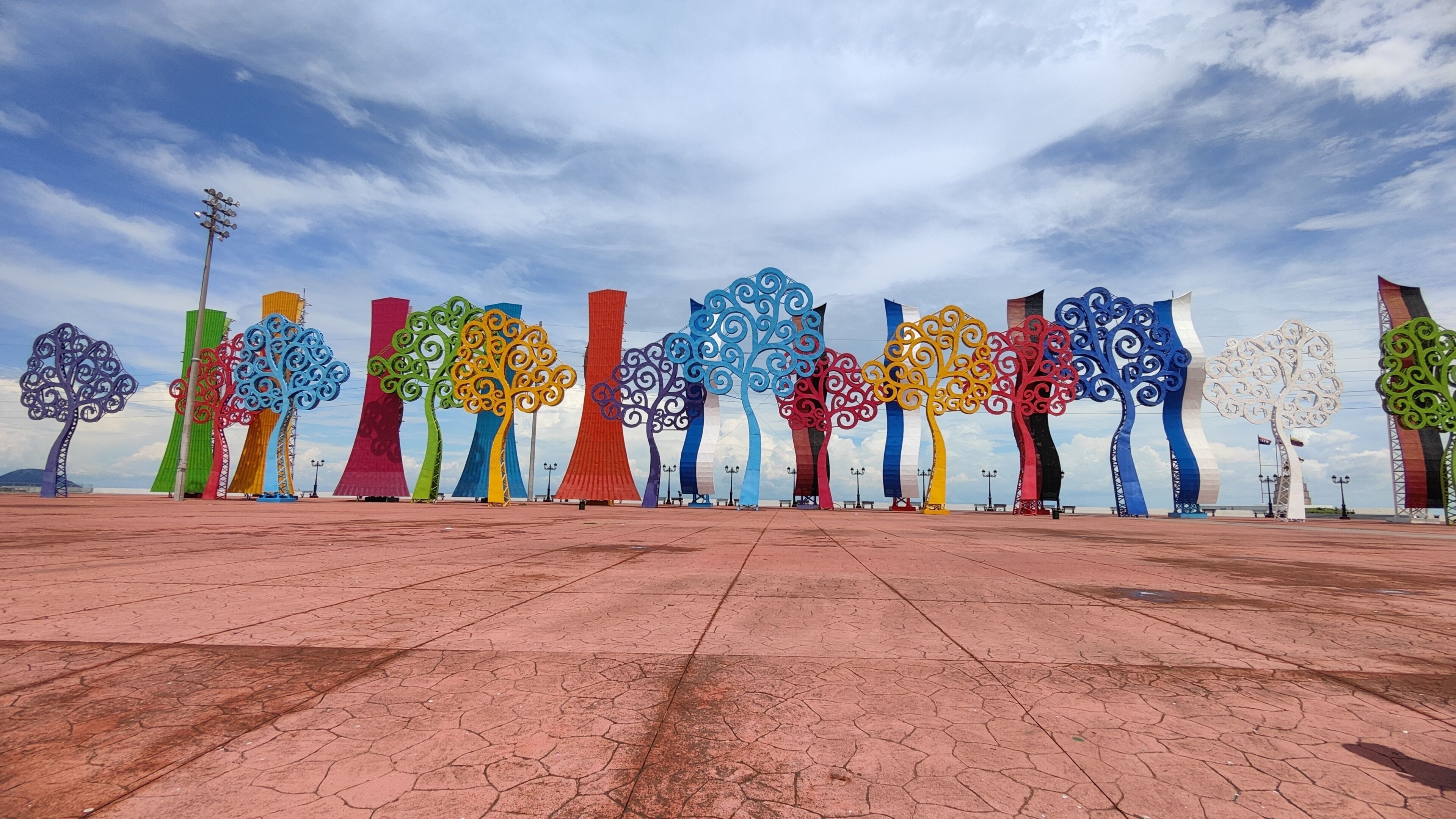 Una serie de coloridas esculturas abstractas de árboles en una plaza.