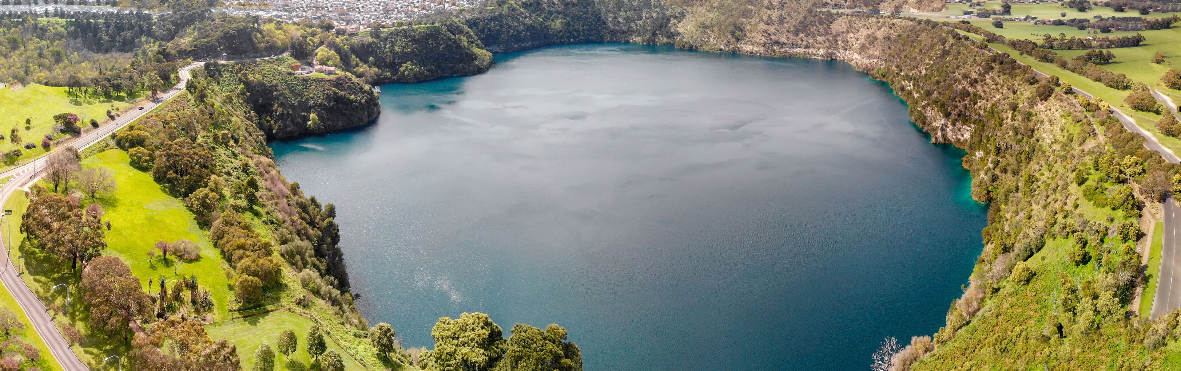 A large, calm lake surrounded by lush greenery and hills.