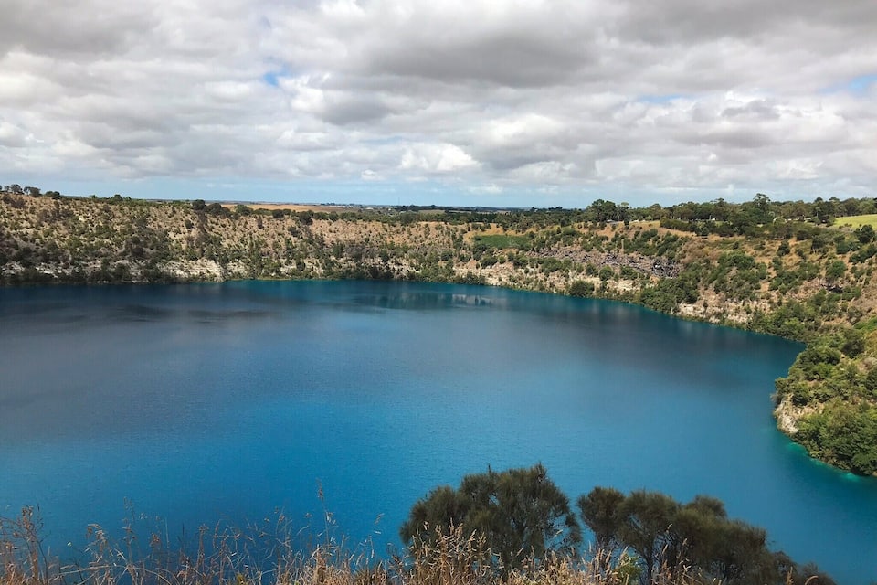 A large, clear blue lake surrounded by hills with sparse vegetation.