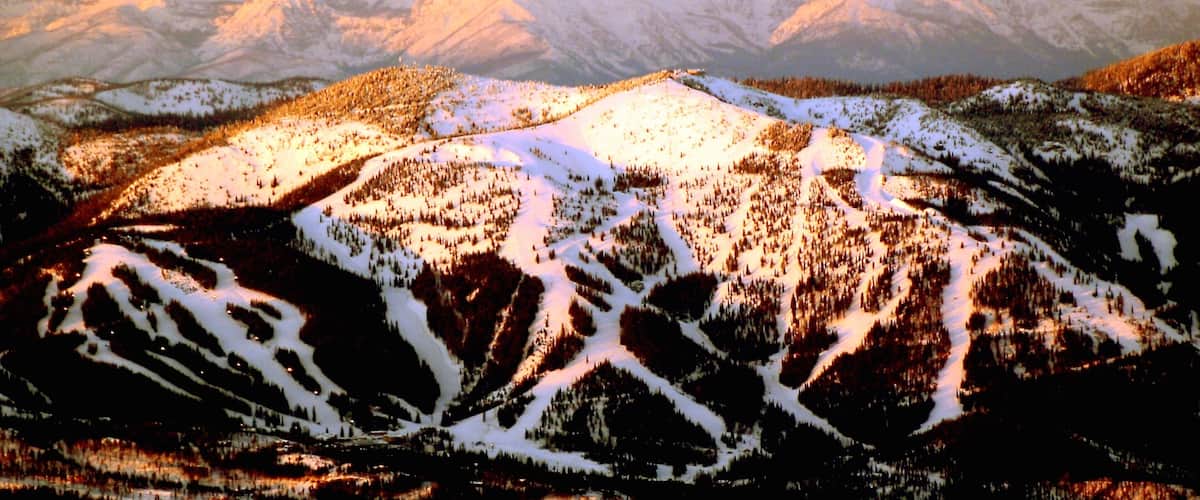 A snow-covered mountain range with a forested valley.