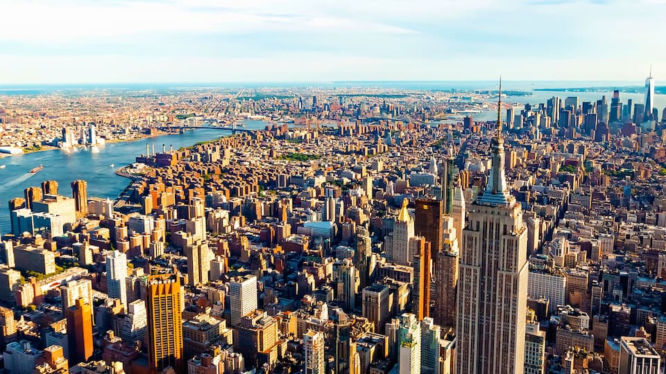 A dense urban landscape with a prominent river, numerous skyscrapers, and a distinctive tall tower.