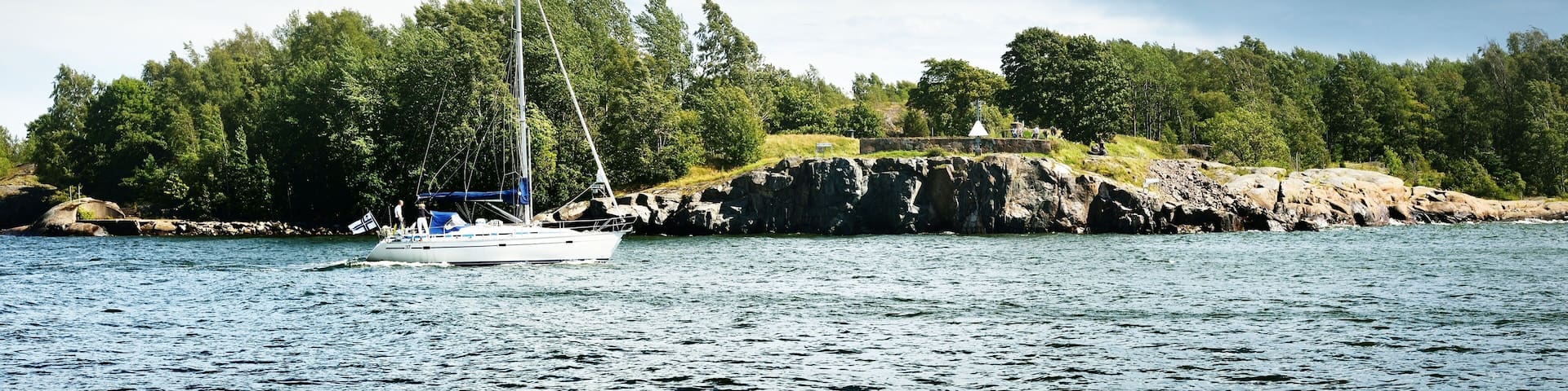 Small sailboat sailing against Finland shoreline