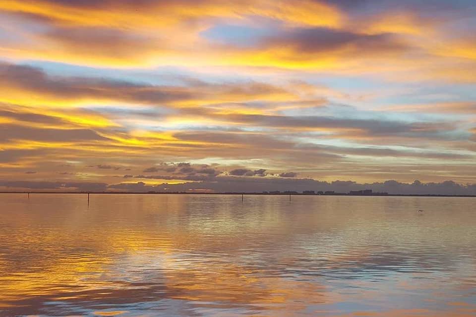 A sunset over a calm body of water with a skyline in the distance.