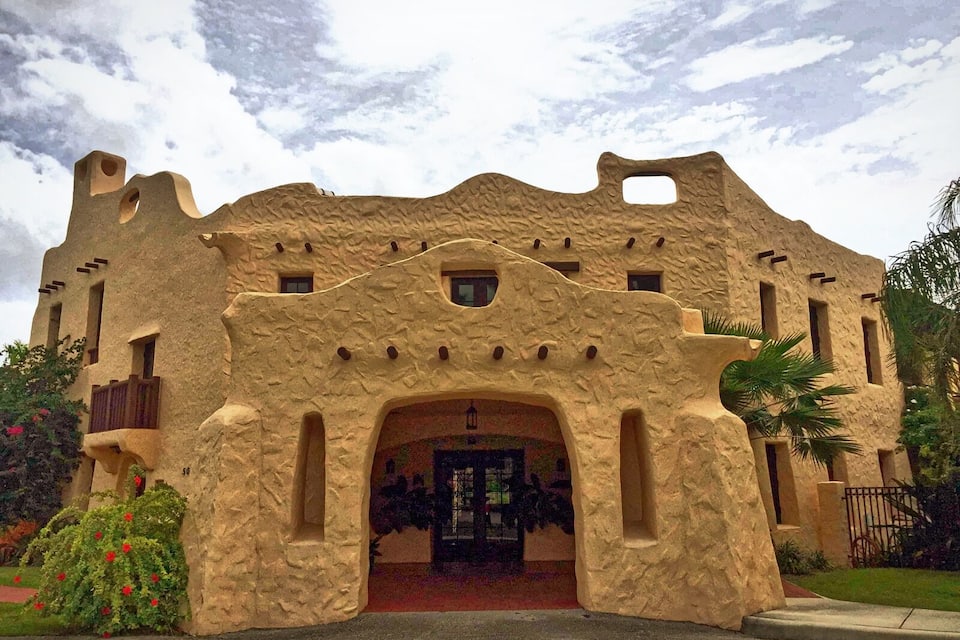 Um edifício com estilo arquitetônico único, apresentando fachada texturizada e entrada em arco.