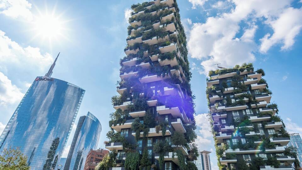 Ein modernes Hochhaus mit vertikalen Gärten, umgeben von weiteren Wolkenkratzern.