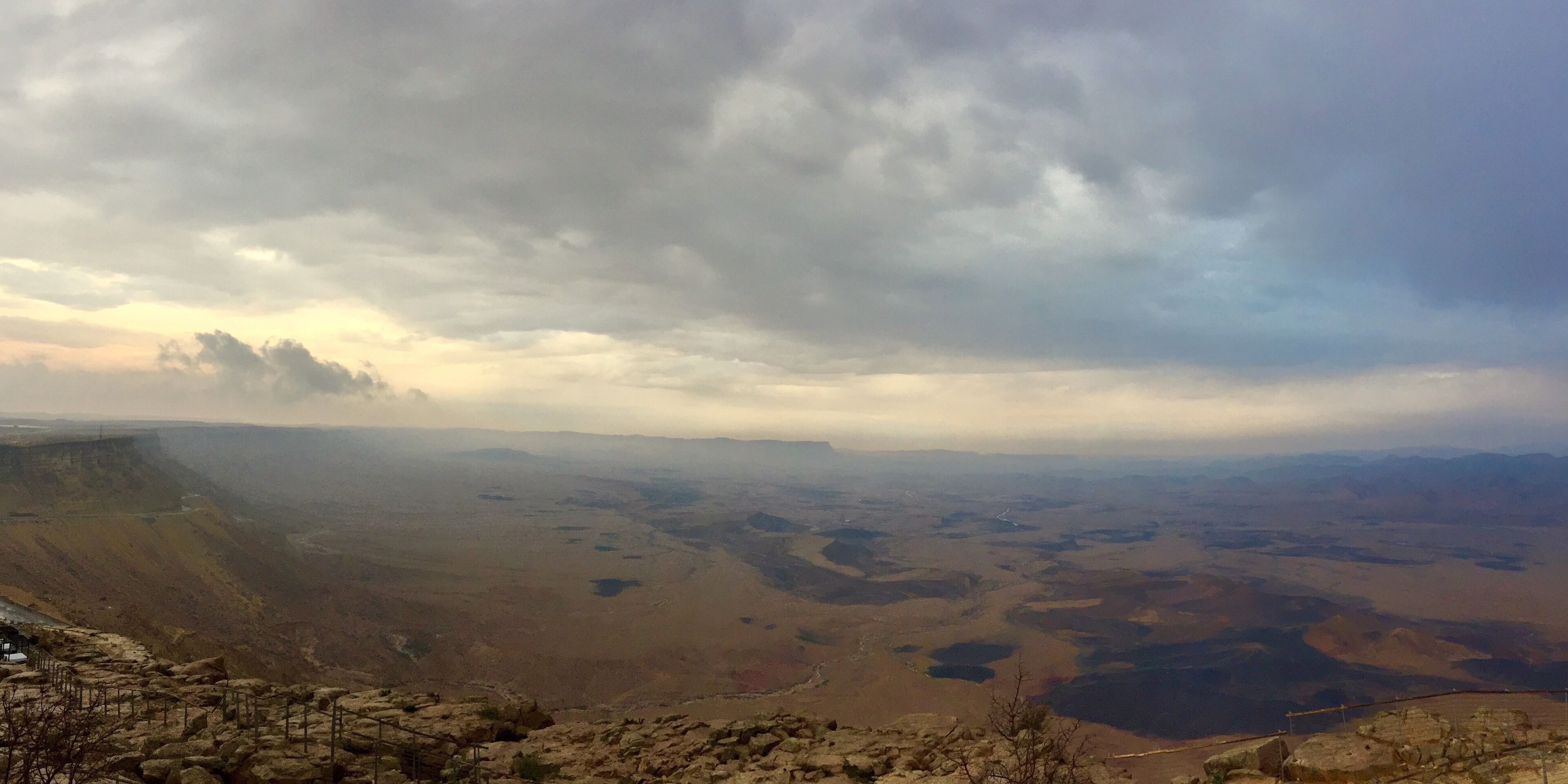 A mountainous landscape with a valley and a cloudy sky.