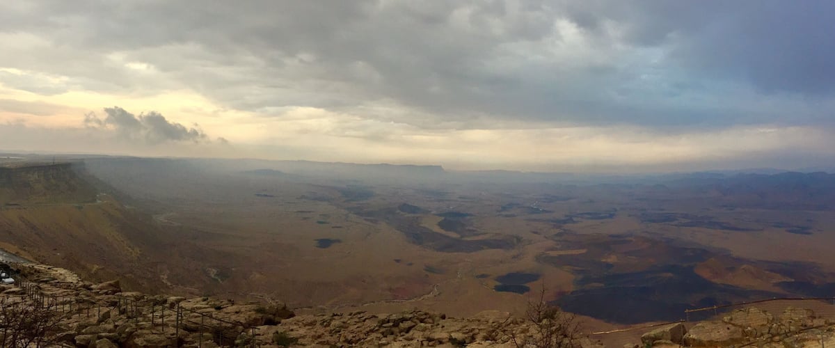 A mountainous landscape with a valley and a cloudy sky.