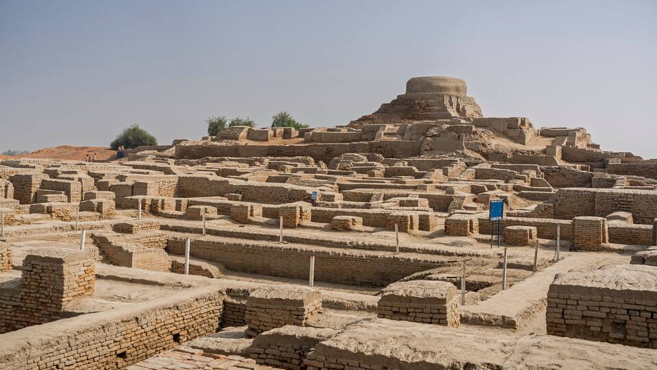Ancient ruins with brick structures and a large mound.