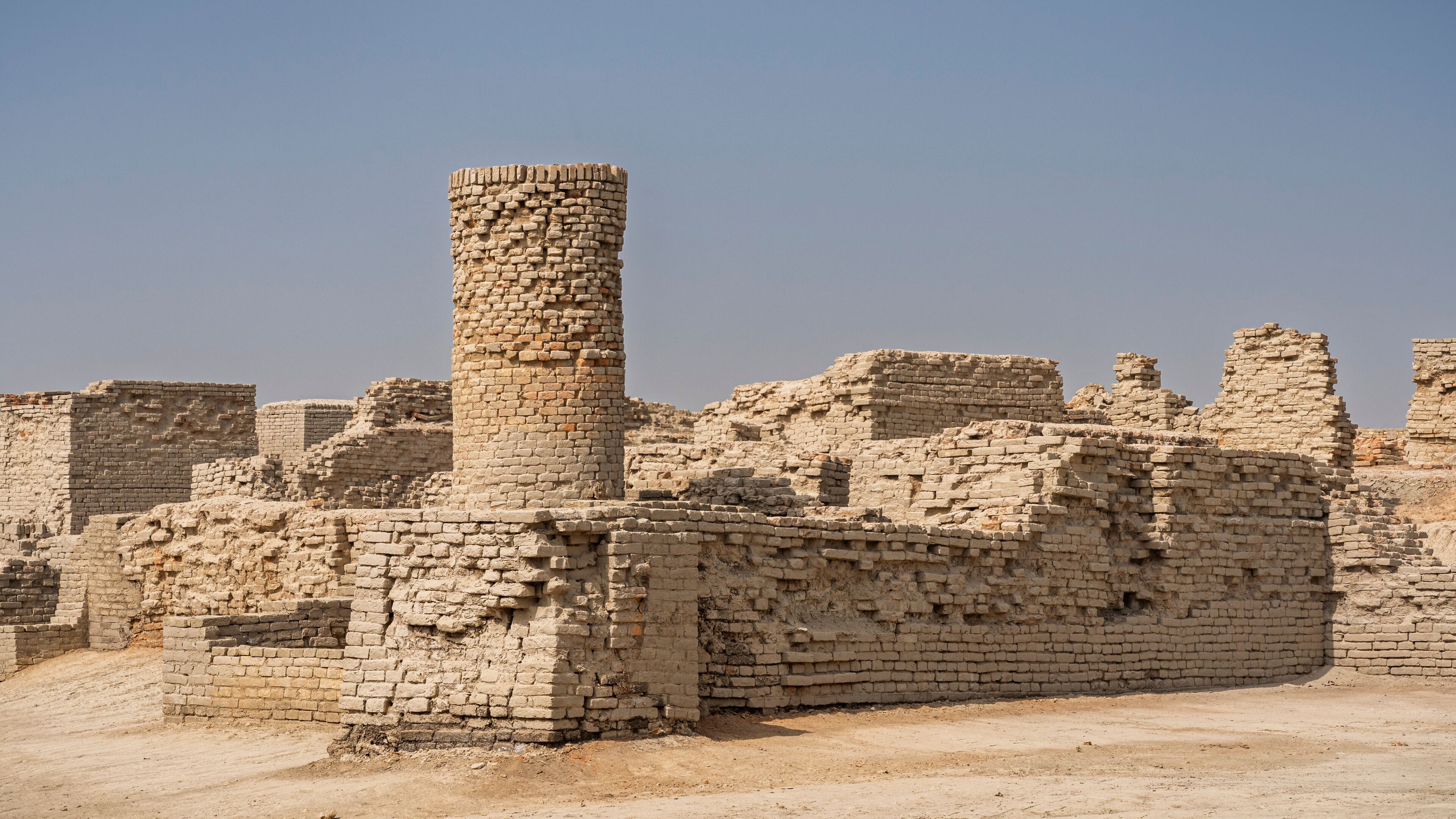 Cityscape view of ancient house walls and long brick well in archaeological ruins of UNESCO World Heritage Mohenjo-Daro, Larkana, Sindh, Pakistan