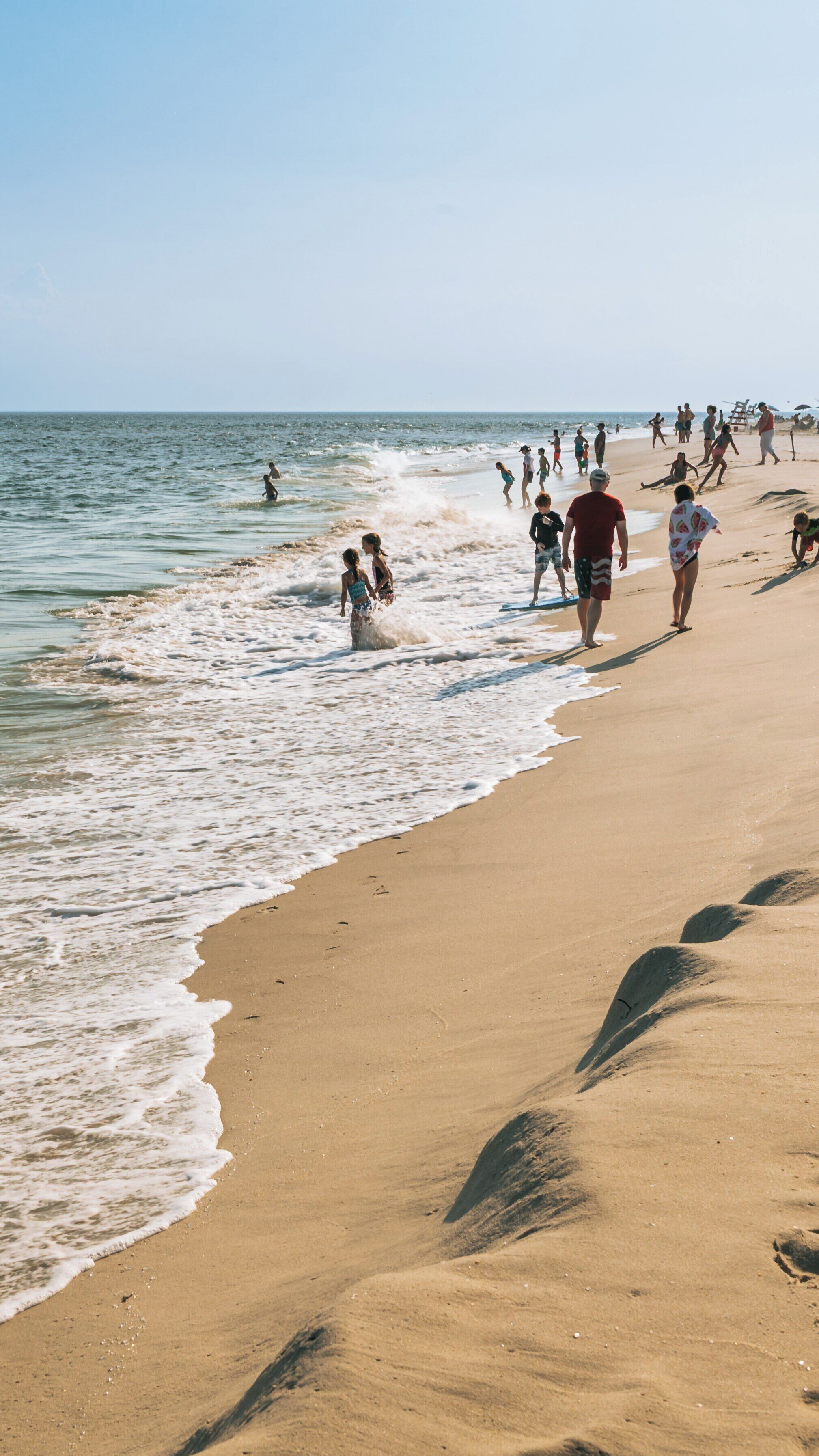 Enjoying a sunny day at Poverty Beach in Cape May, New Jersey with families playing by the water's edge