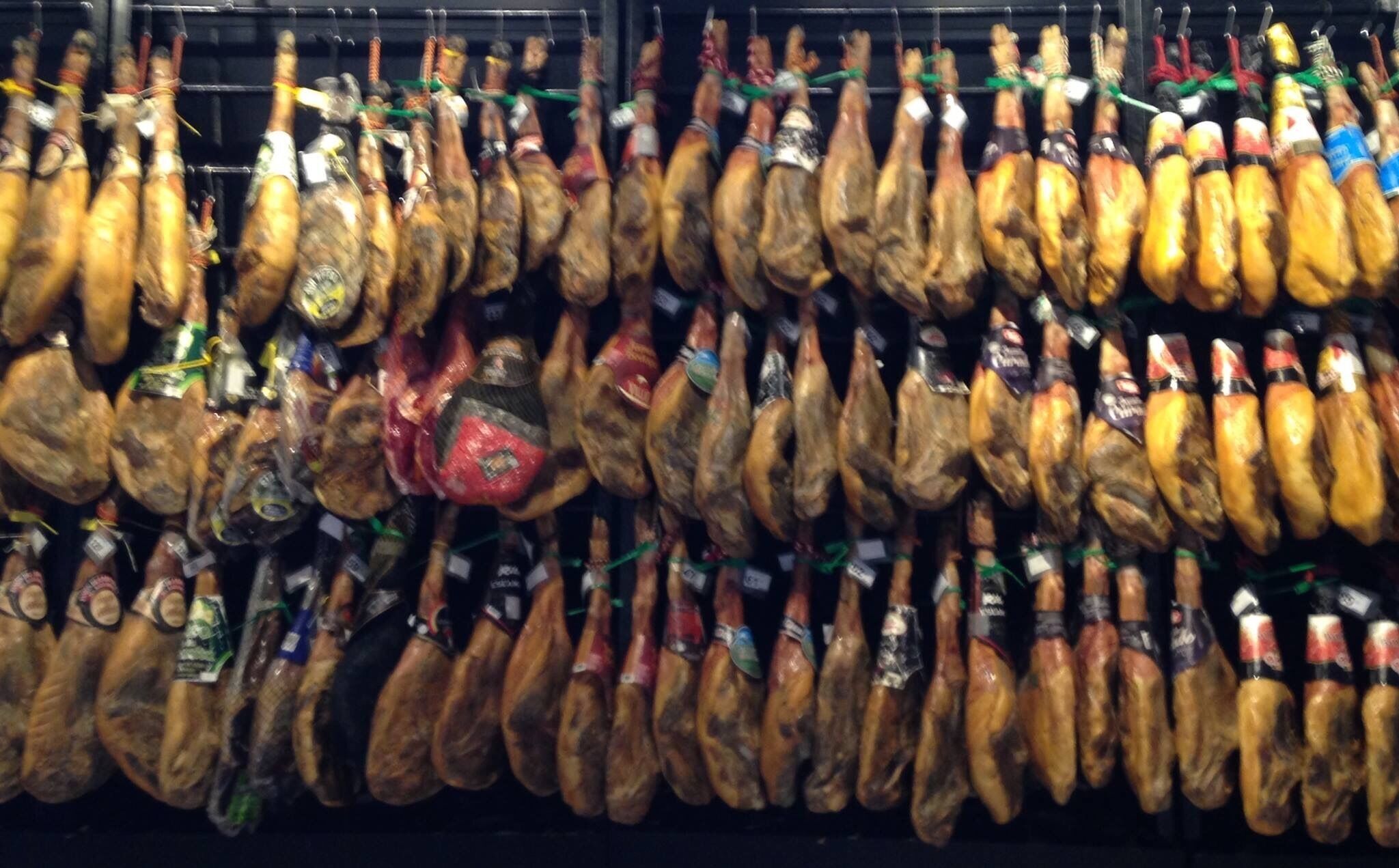 A display of various types of cured meats hanging in a store.