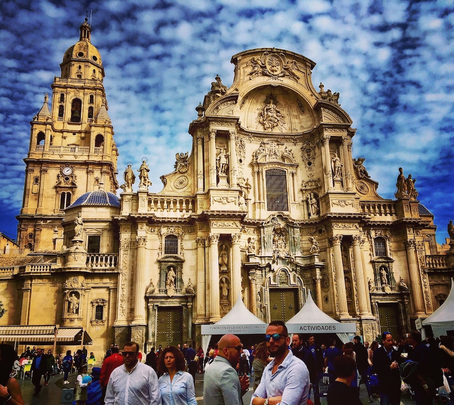 A historic cathedral with intricate architecture and a crowd of people in front.