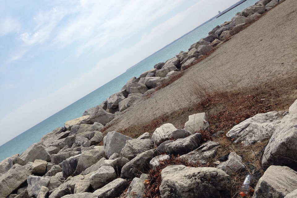 A rocky shoreline with large boulders and a clear view of the sea.