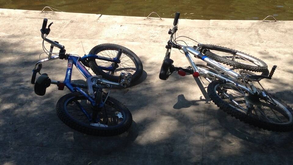 Two bicycles parked on a concrete surface near a body of water.