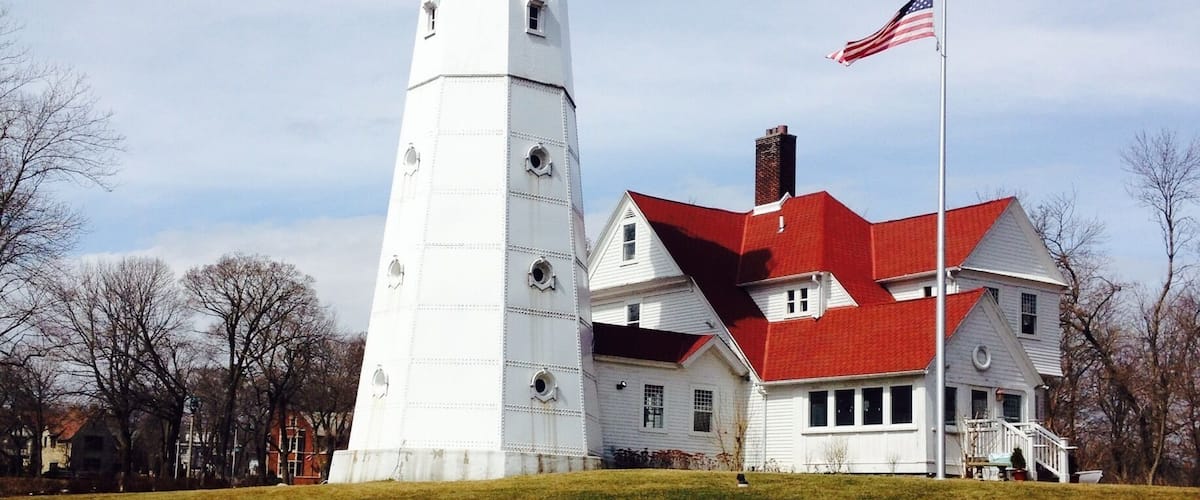 A lighthouse and a house with a red roof.