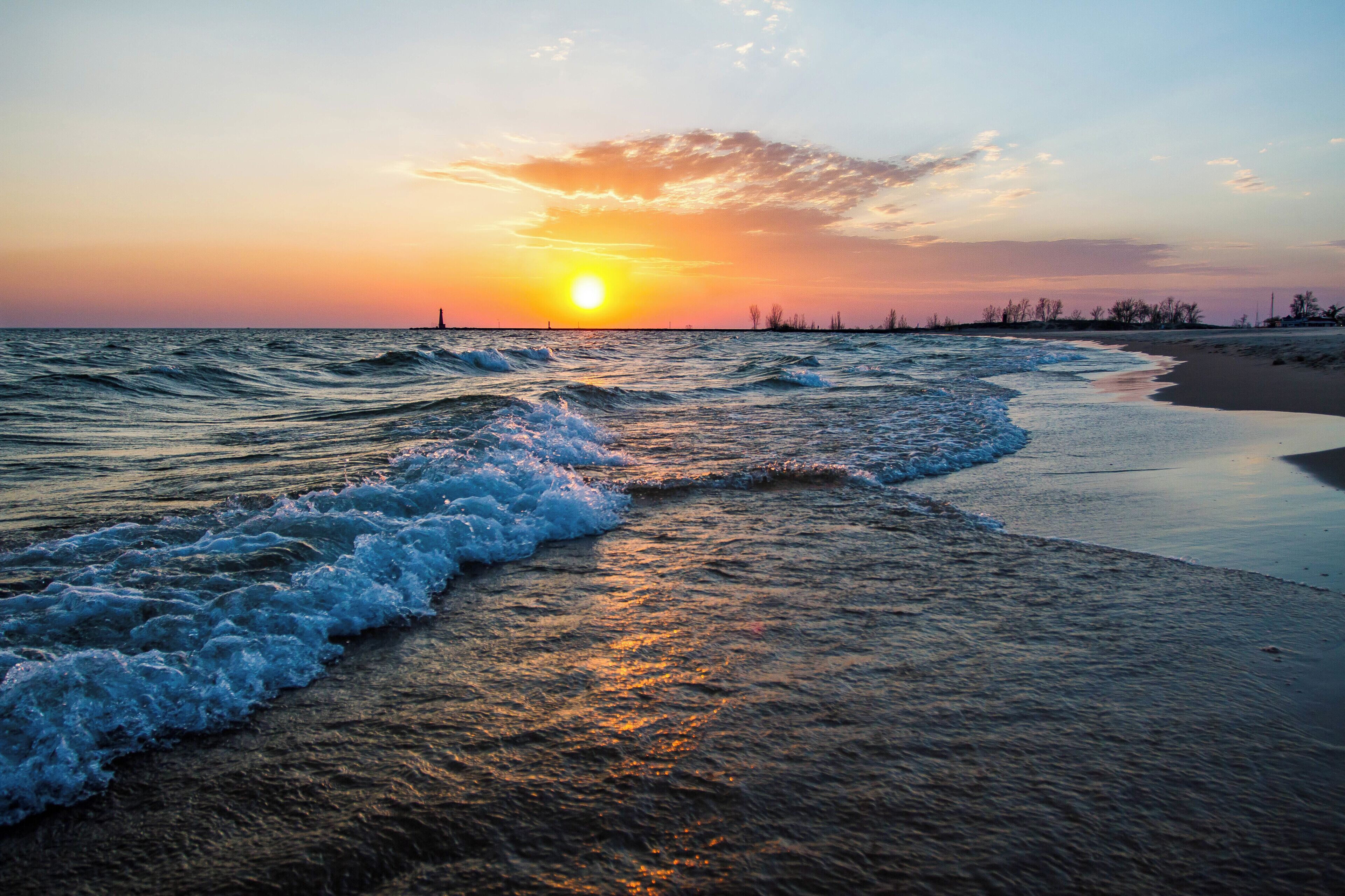 Una puesta de sol sobre una playa con olas rompiendo suavemente en la orilla.
