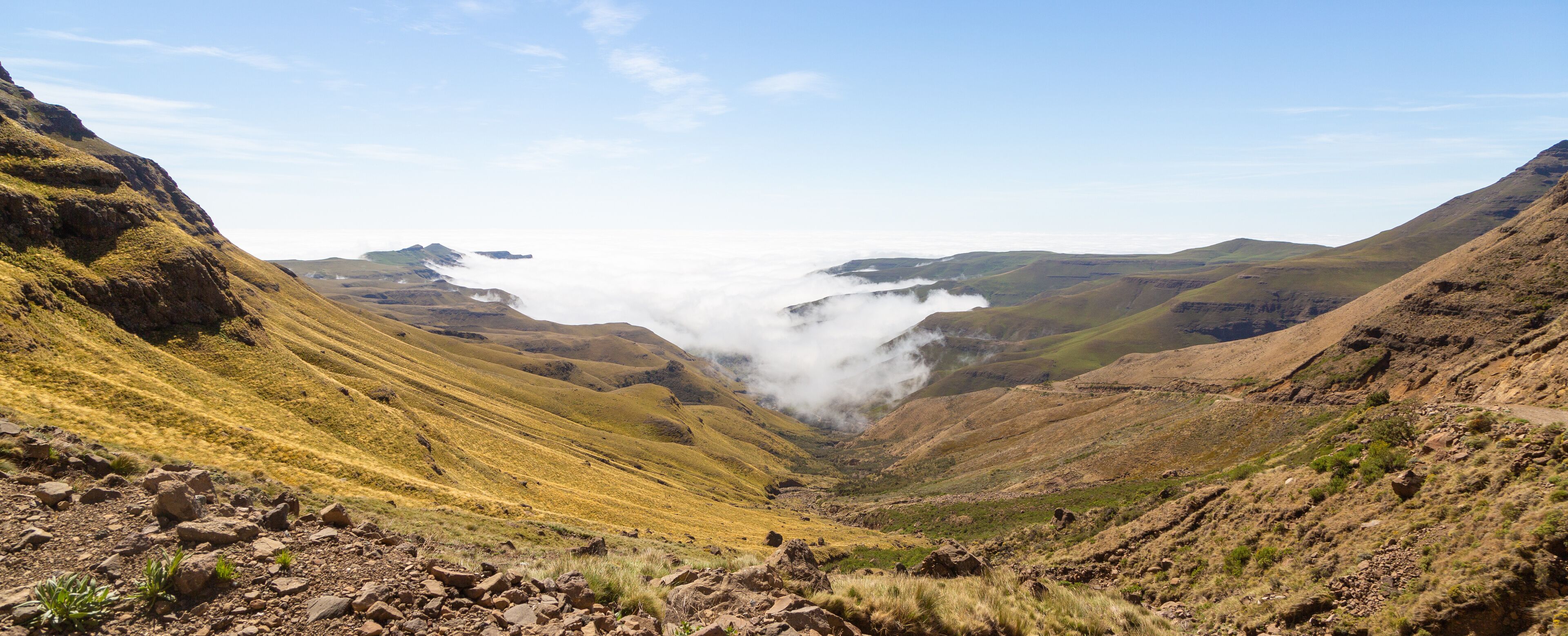 A valley with rocky terrain and a mountain range in the background.