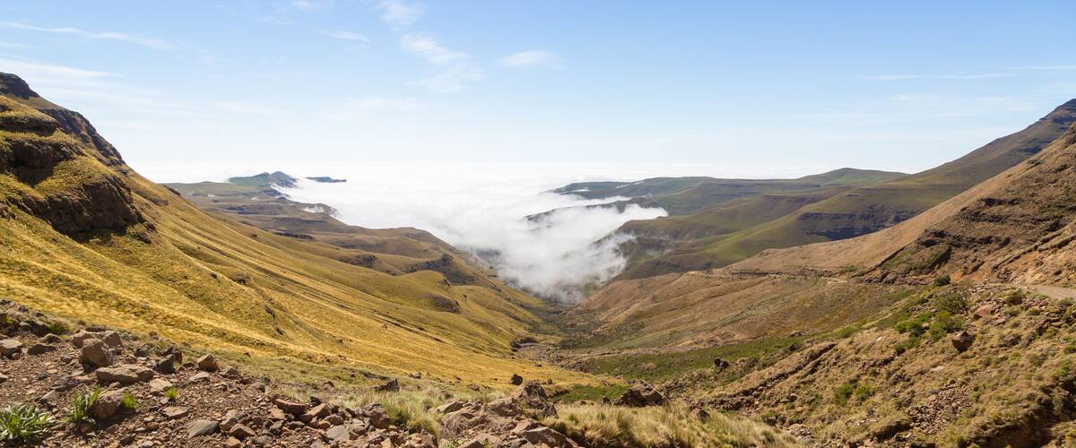 A valley with rocky terrain and a mountain range in the background.