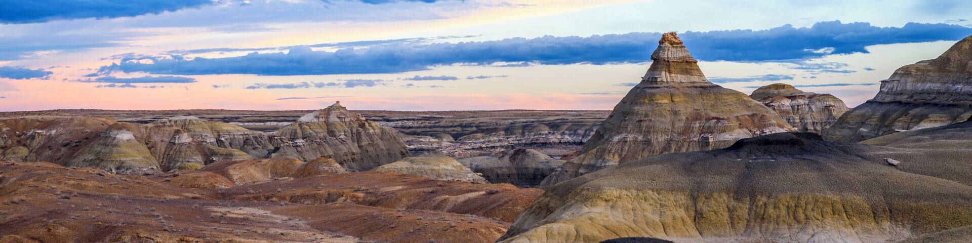 A rugged landscape with eroded hills and a clear sky.