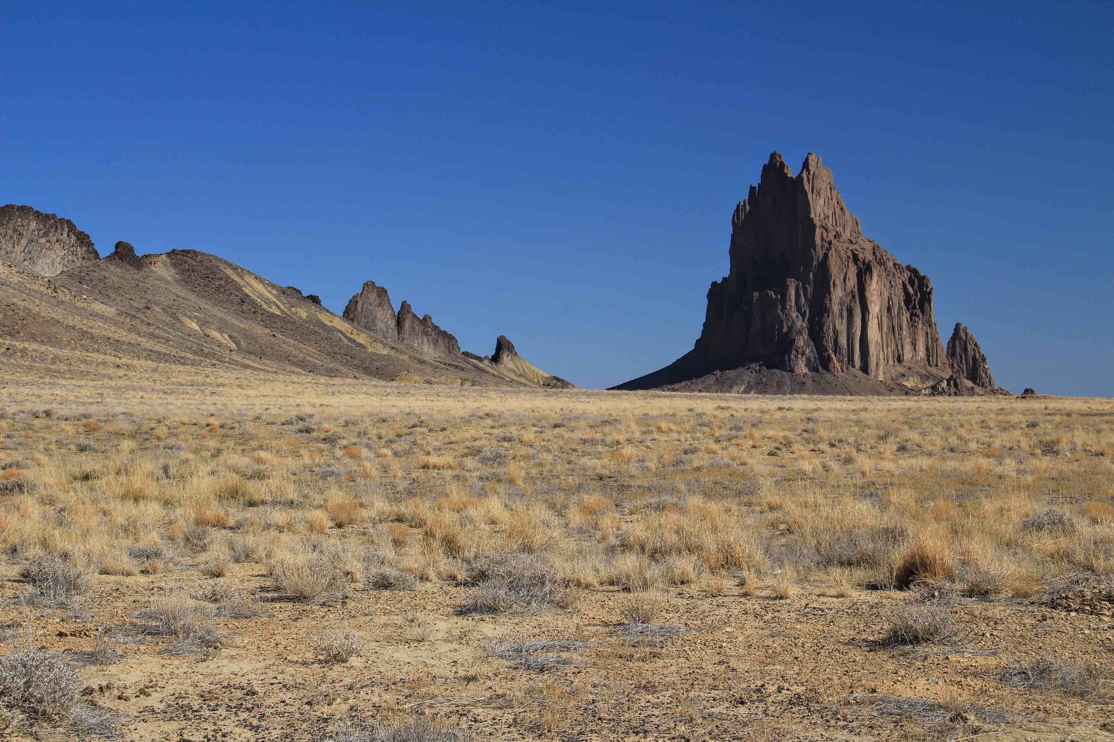 The Ship Rock formation in New Mexico is a 1583 ft (482 m) tall remains of an ancient volcano. The elevation at the peak is over 7100 feet above sea level. Leading up to the rock is a long rift along the ground forming what appears to be the ruins of a huge stone wall. Great for hiking and easily accessible to visit. We didn't see any other people when we visited. It is located about 10 miles south of the town of Ship Rock and can be seen from town. There is a highway that passes fairly close with a rough dirt access road to get even closer. The Ship Rock is a sacred Navajo site and I was advised that climbing the rock is no longer permitted.