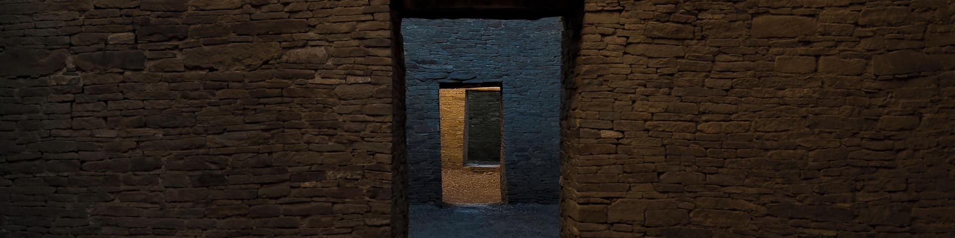 A stone wall with a rectangular doorway leading to a dark interior.