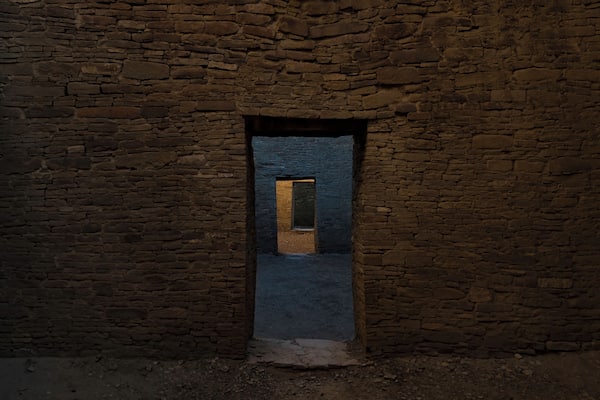 A stone wall with a rectangular doorway leading to a dark interior.