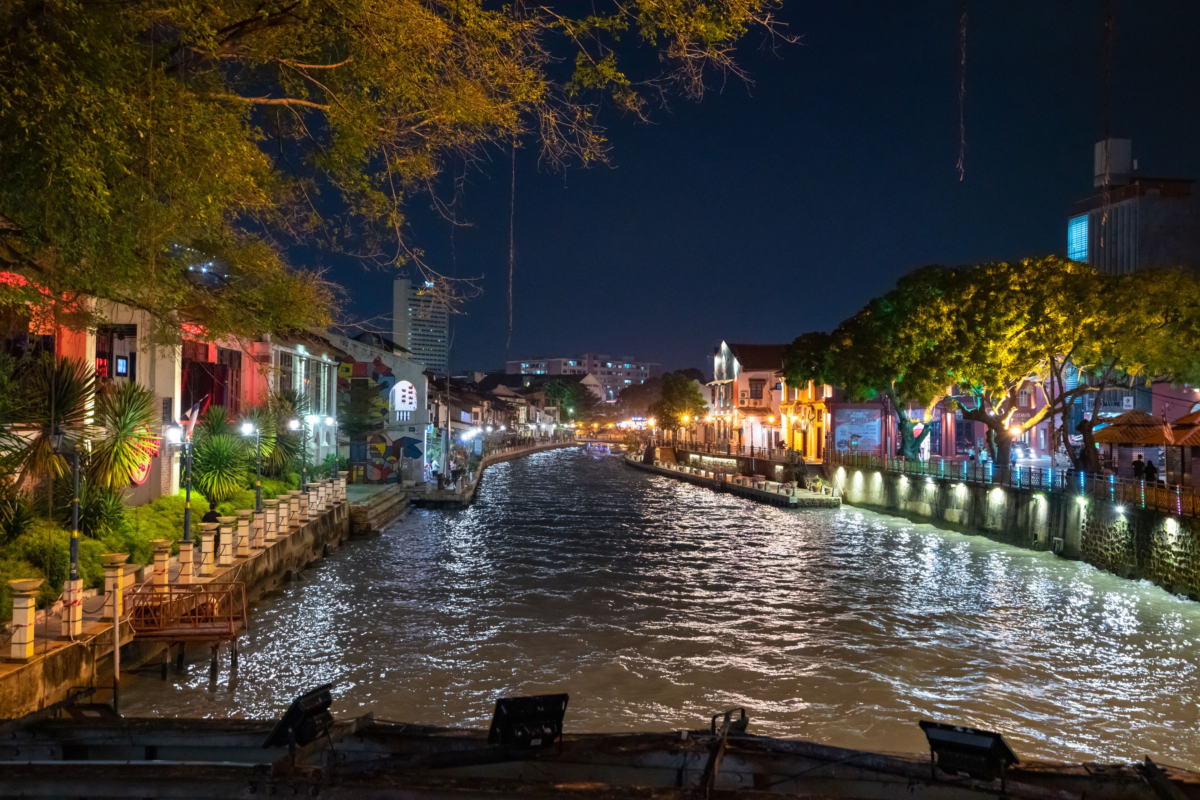 A river with buildings on both sides, illuminated by artificial lights.