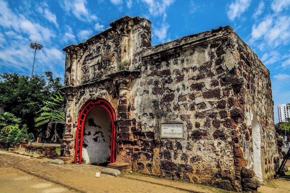 An ancient fortress with a red archway and a weathered stone exterior.